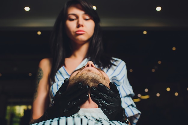 Portrait of man beard in barbershop. Female hand.