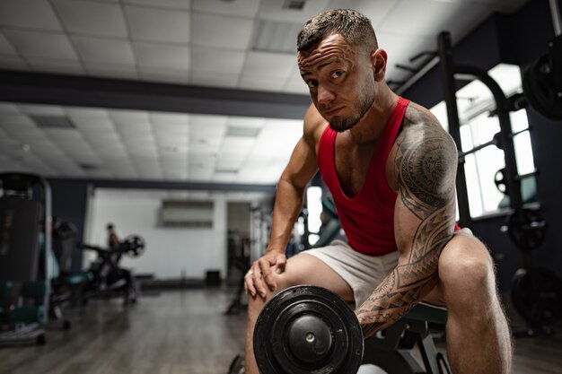 Portrait of man bodybuilder in red shirt in gym