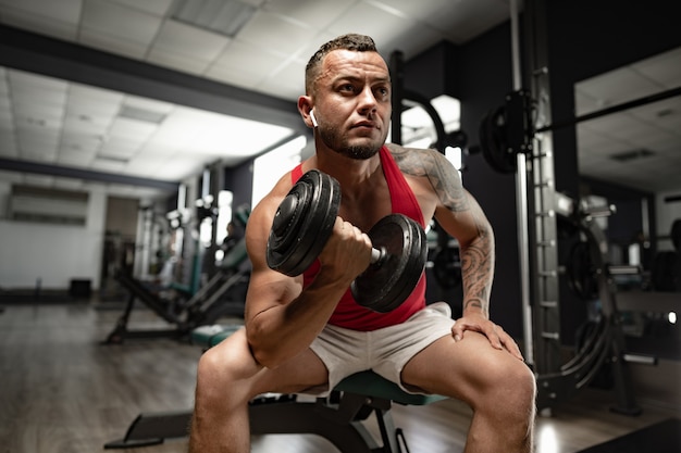 Portrait of man bodybuilder in red shirt in gym