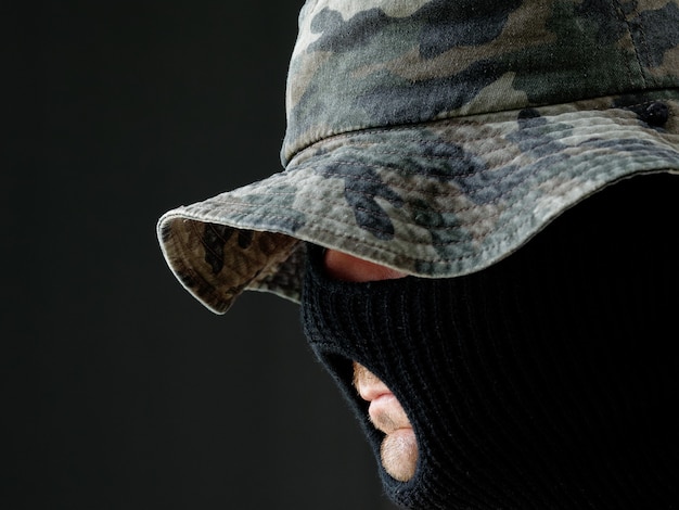 Portrait of a  man in a camouflage Panama hat and a black Balaclava.