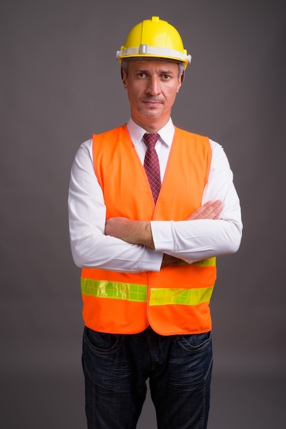 Photo portrait of man construction worker against gray wall