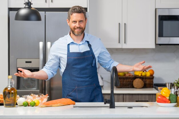 Portrait of man in cook apron preparing food at kitchen handsome man in chef apron preparing raw fis