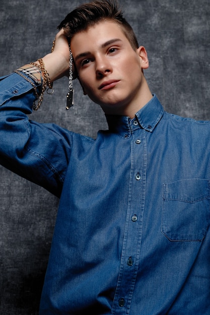 Portrait of man in denim shirt with fashionable bracelets