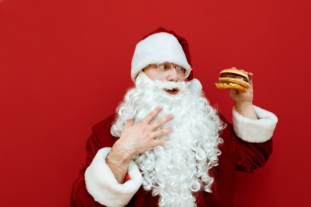 Portrait man dressed as Santa Claus holding burger