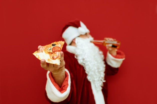 Портрет мужчины в костюме Санта-Клауса, держащего пиццу и пиво