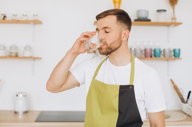 自宅のキッチンで水を飲む男の肖像画