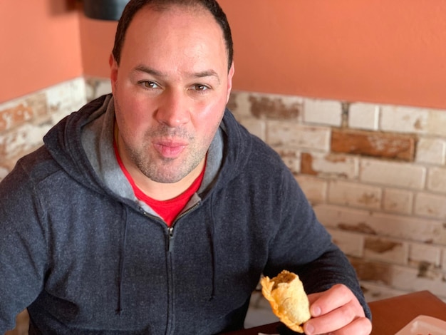 Foto ritratto di un uomo che mangia mentre è seduto contro il muro