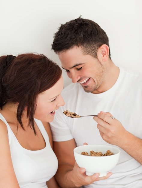 Portrait of a man feeding cereal to his wife in the bedroom