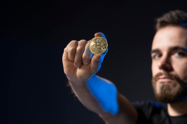 Foto ritratto di un uomo che tiene in mano il bitcoin su uno sfondo nero