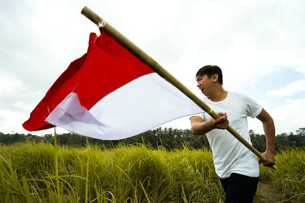 Photo portrait of man holding a flag of indonesia