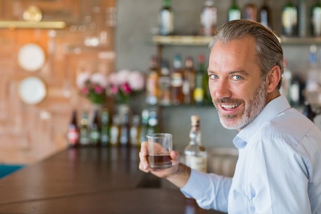 Portrait of man holding glass of whiskey