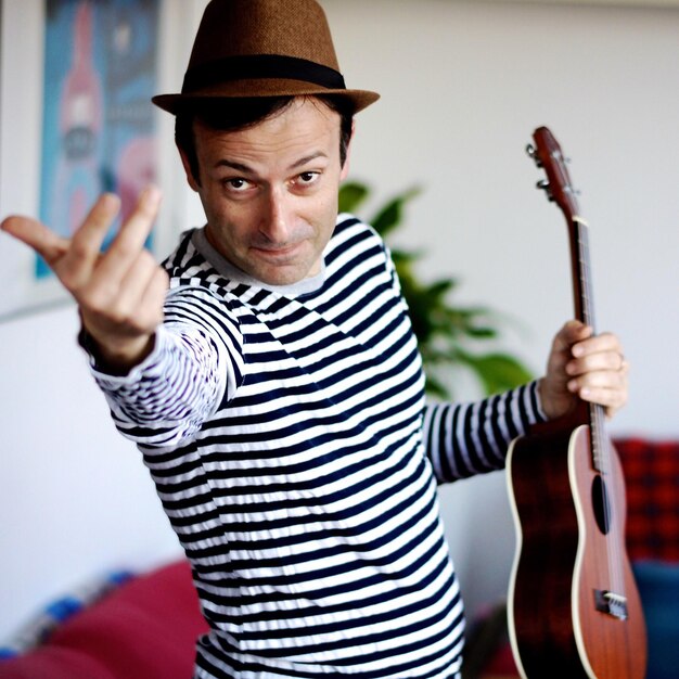 Foto ritratto di un uomo che tiene la chitarra in piedi a casa