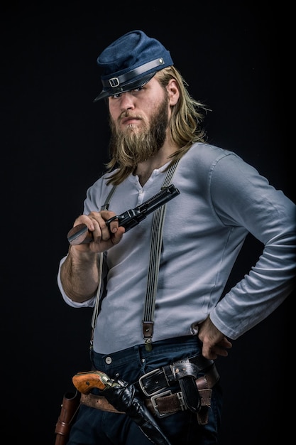portrait of man holding gun while standing against black background