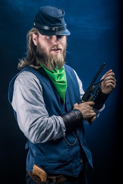 portrait of man holding gun while standing against black background