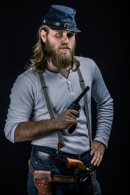 portrait of man holding gun while standing against black background