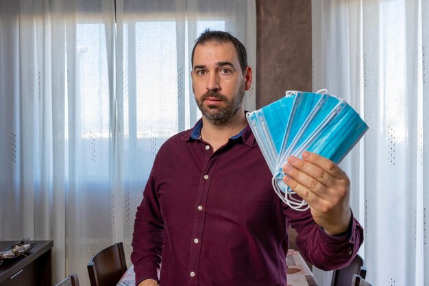 Portrait of man holding ice cream standing against window