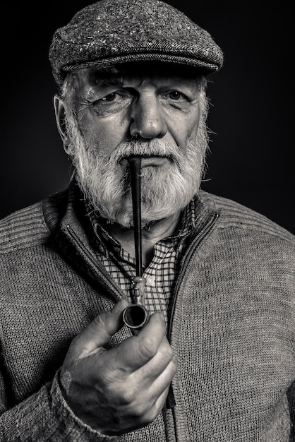 Portrait of man holding smoking pipe against black background