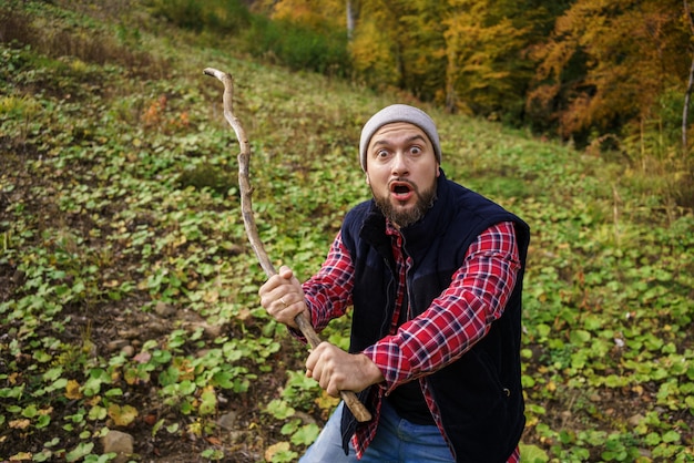 Portrait of a man holding a stick in the forest