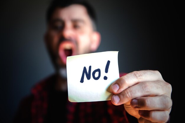 Portrait of man holding text against black background