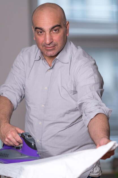 Photo portrait of man ironing clothes at home