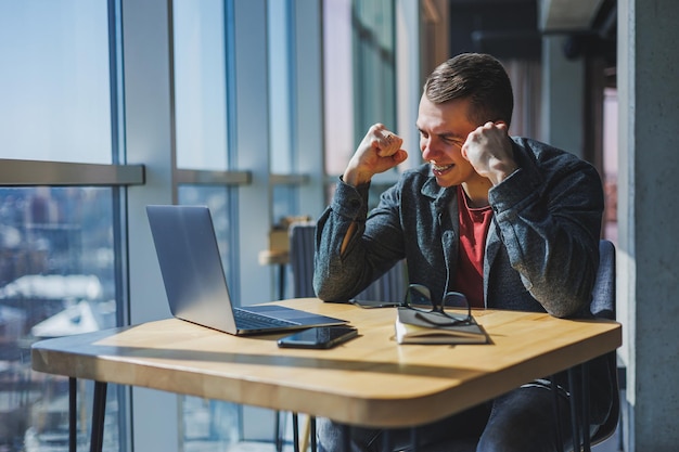 Portrait of a man it professional working remotely with a
modern laptop sitting at a table and smiling at the camera during a
break a happy human programmer in vision correction glasses