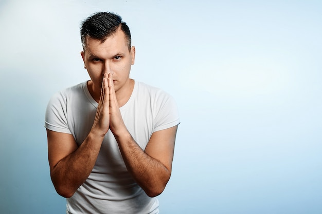 Portrait of a man on a light background, folded his hands in front of him in the palms of his hands. 