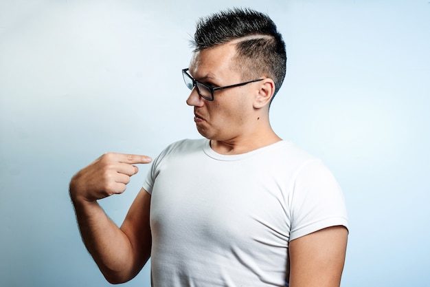 Portrait of a man on a light background, showing a finger at himself, it's me. 