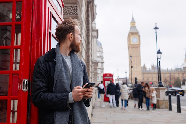 スマートフォンを持って立ってよそ見をしている男性のポートレート