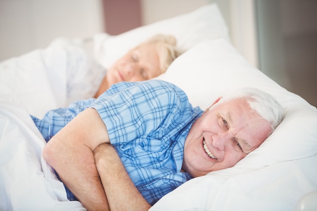 Portrait of man lying with his wife on bed