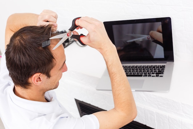 Portrait of a man makes a haircut for himself during quarantine