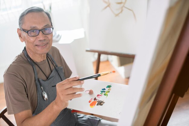 portrait of man painting on canvas at home