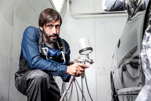 Foto ritratto di un uomo che dipinge una macchina in fabbrica