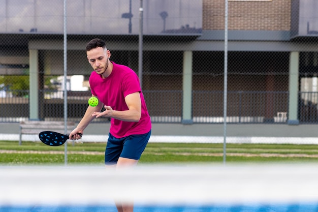 Portrait of a man performing a serve in pickleball Sporty man pickleball tennis player trains on the outdoor court using a racket to hit ball