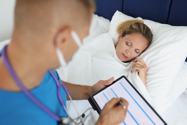 Portrait of man physician making prescription for ill woman examining of patient doctor typing