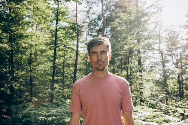 portrait of a man in a pink tshirt in the forest in the sunlight backlight