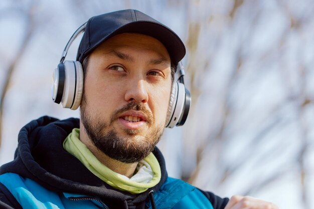 Portrait of a man running in the park and listening to music through wireless headphones