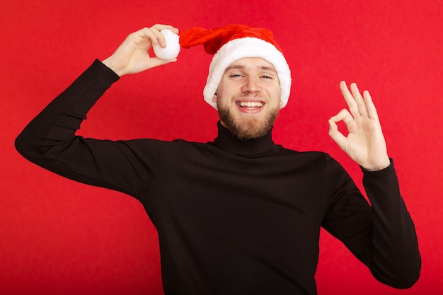 Foto ritratto di un uomo con un cappello di babbo natale che mostra con le dita che tutto va bene