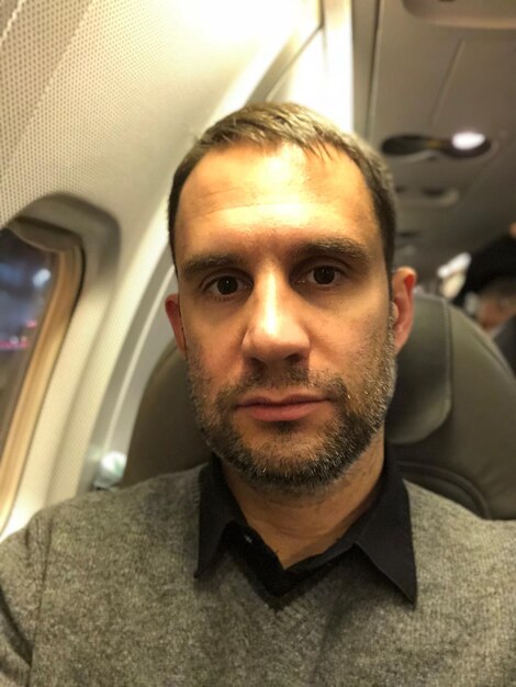 Foto ritratto di un uomo seduto in aereo