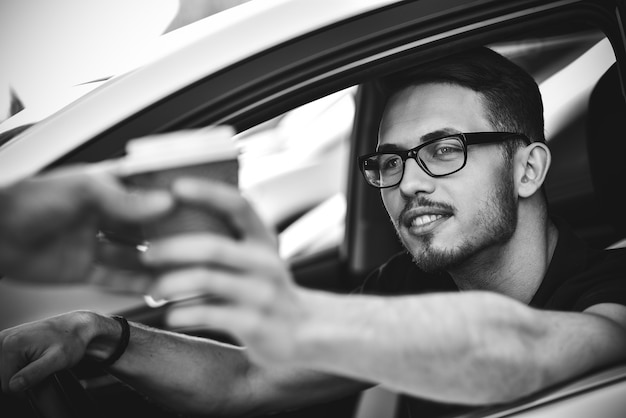 Portrait of man sitting in car and buying coffee to go