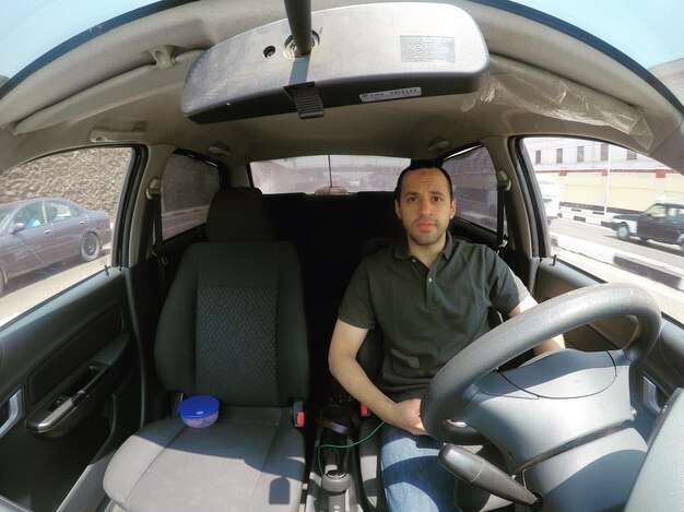 Photo portrait of man sitting in car