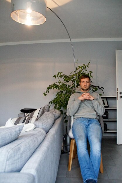 Foto ritratto di un uomo seduto su una sedia nel soggiorno di casa