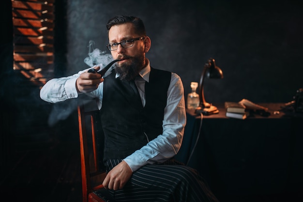 Portrait of man sitting on chair and smoking pipe