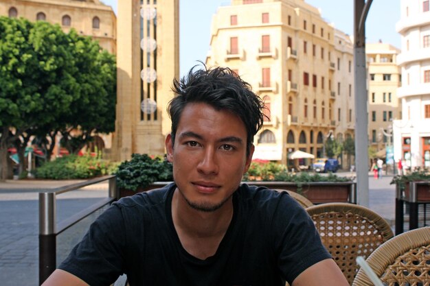 Photo portrait of man sitting in city