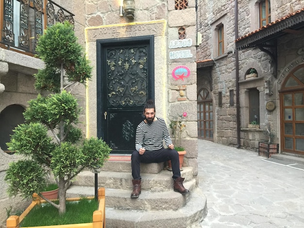 Photo portrait of man sitting on staircase at entrance