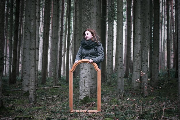 Photo portrait of man sitting on tree trunk in forest