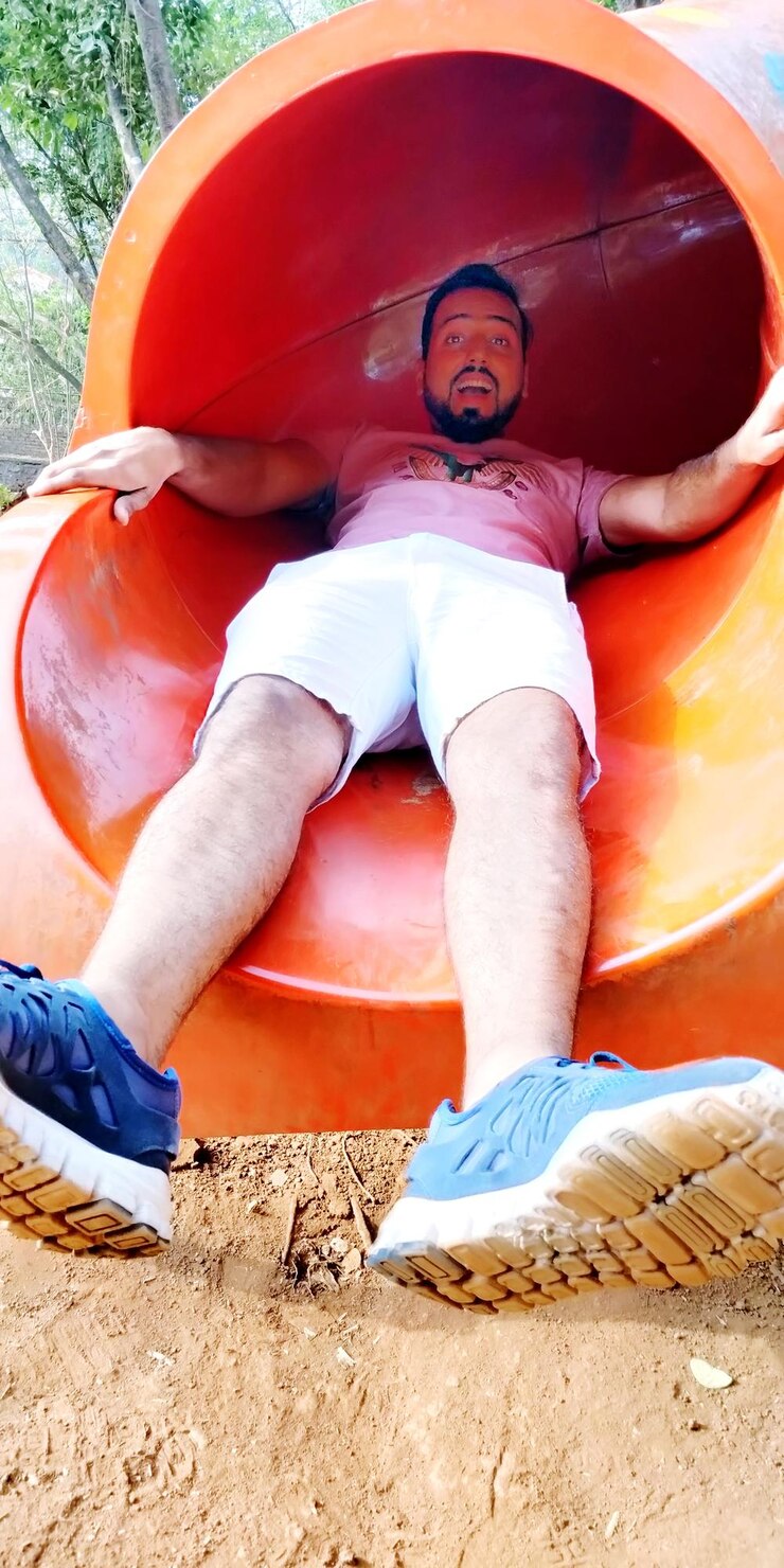 Photo portrait of man sliding on slide at park