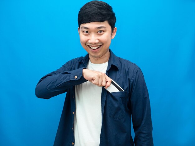 Portrait man smile face gesture pick up credit card out of shirt pocket blue background