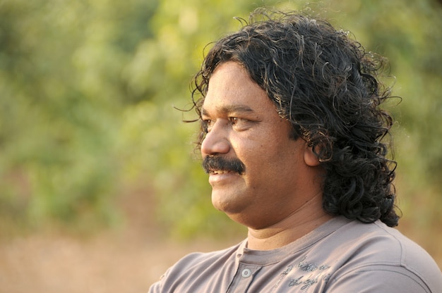 Photo portrait of a man smiling and posing outdoors.