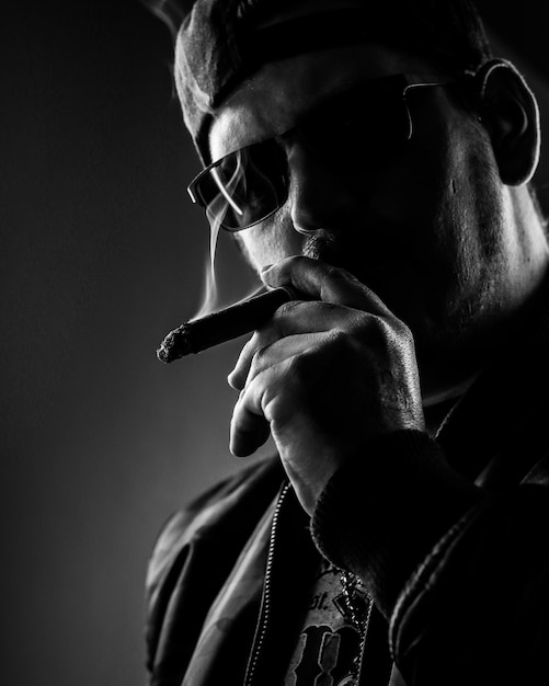 Photo portrait of man smoking cigar on black background