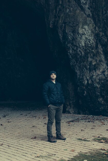 Foto ritratto di un uomo in piedi contro una grotta